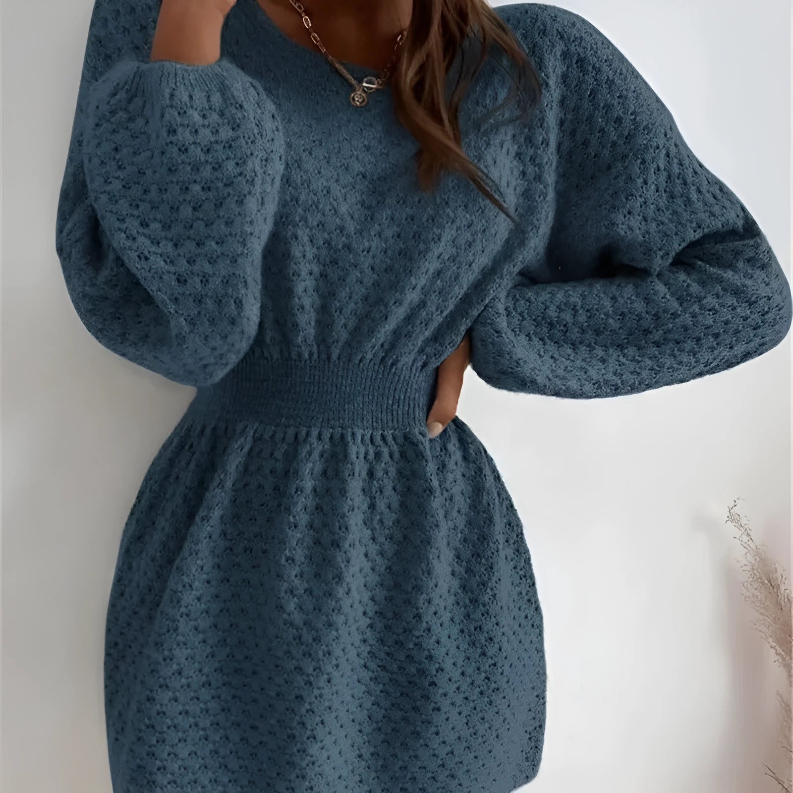Blue women's knitted dress with hand-crocheted floral details, a round neck, and a fitted waist.