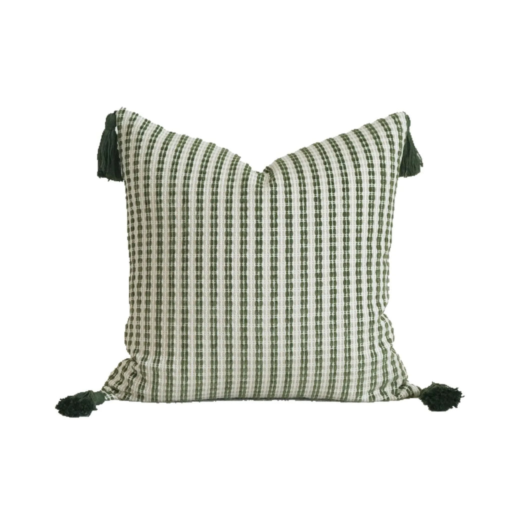 Green striped and leaf patterned hotel pillow with tassel trim on a bed.