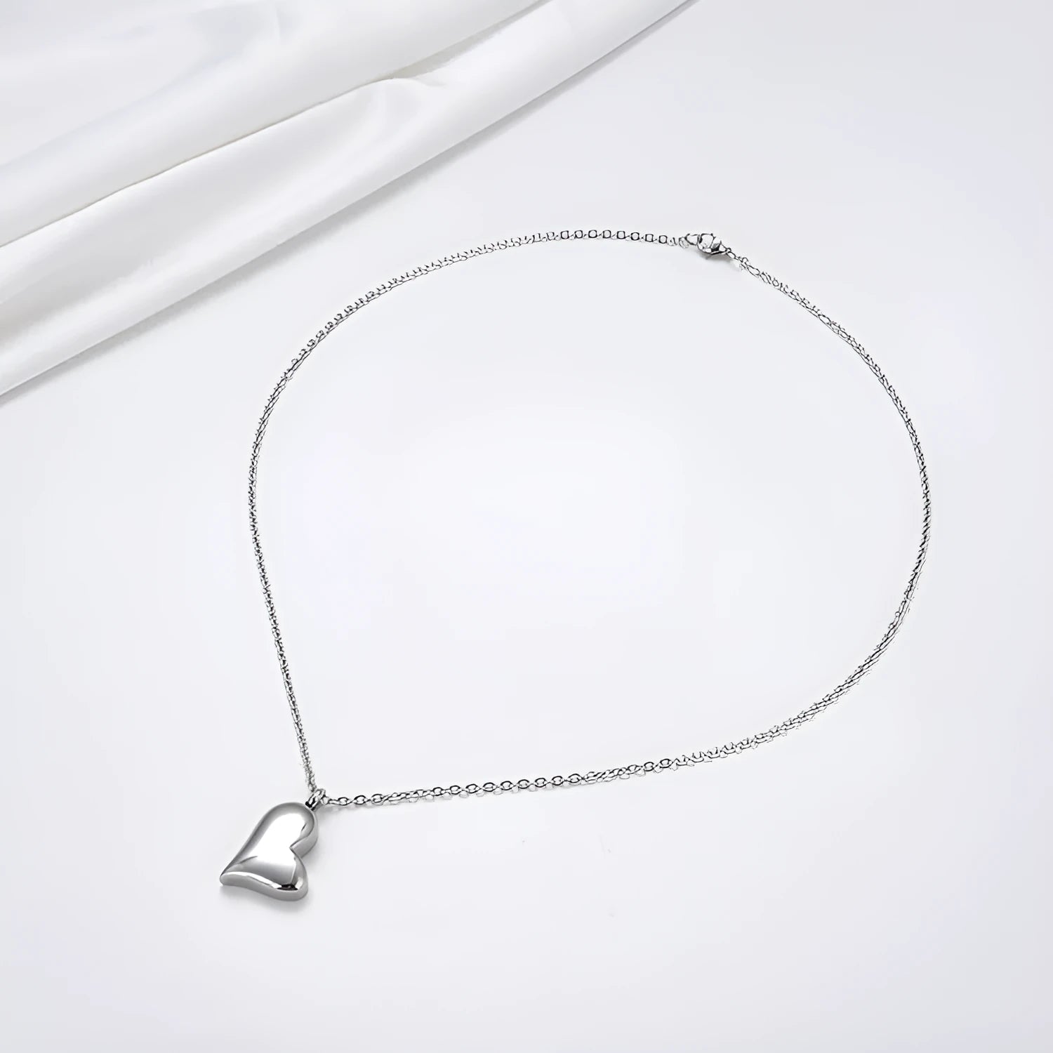 Silver curved peach heart pendant on a stainless steel necklace chain with an extension.