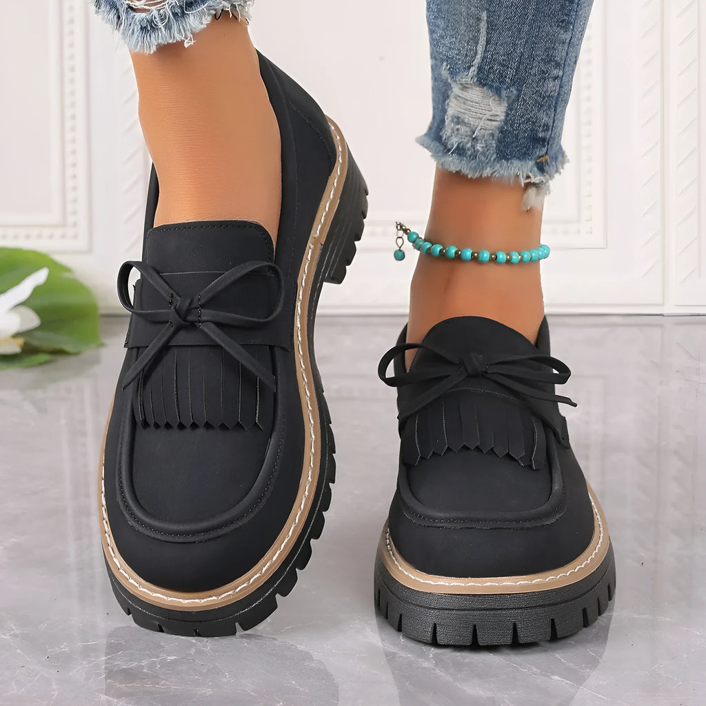 Black plus size women's loafers with a tassel and bowknot on a round toe, low top design.