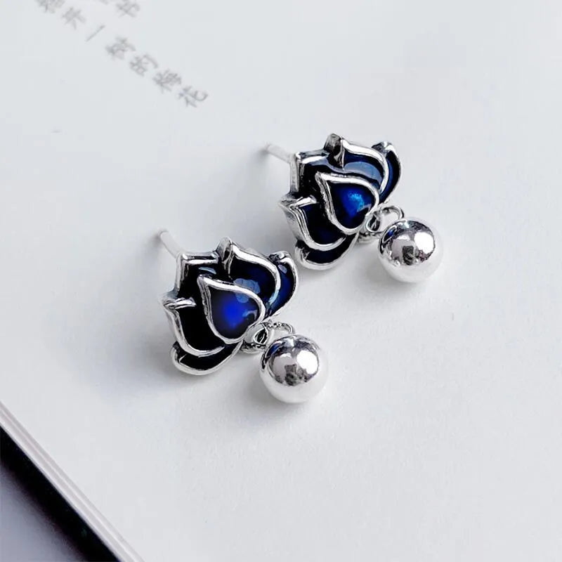 Blue alloy lotus flower ear studs with a seedpod tassel on silver posts.