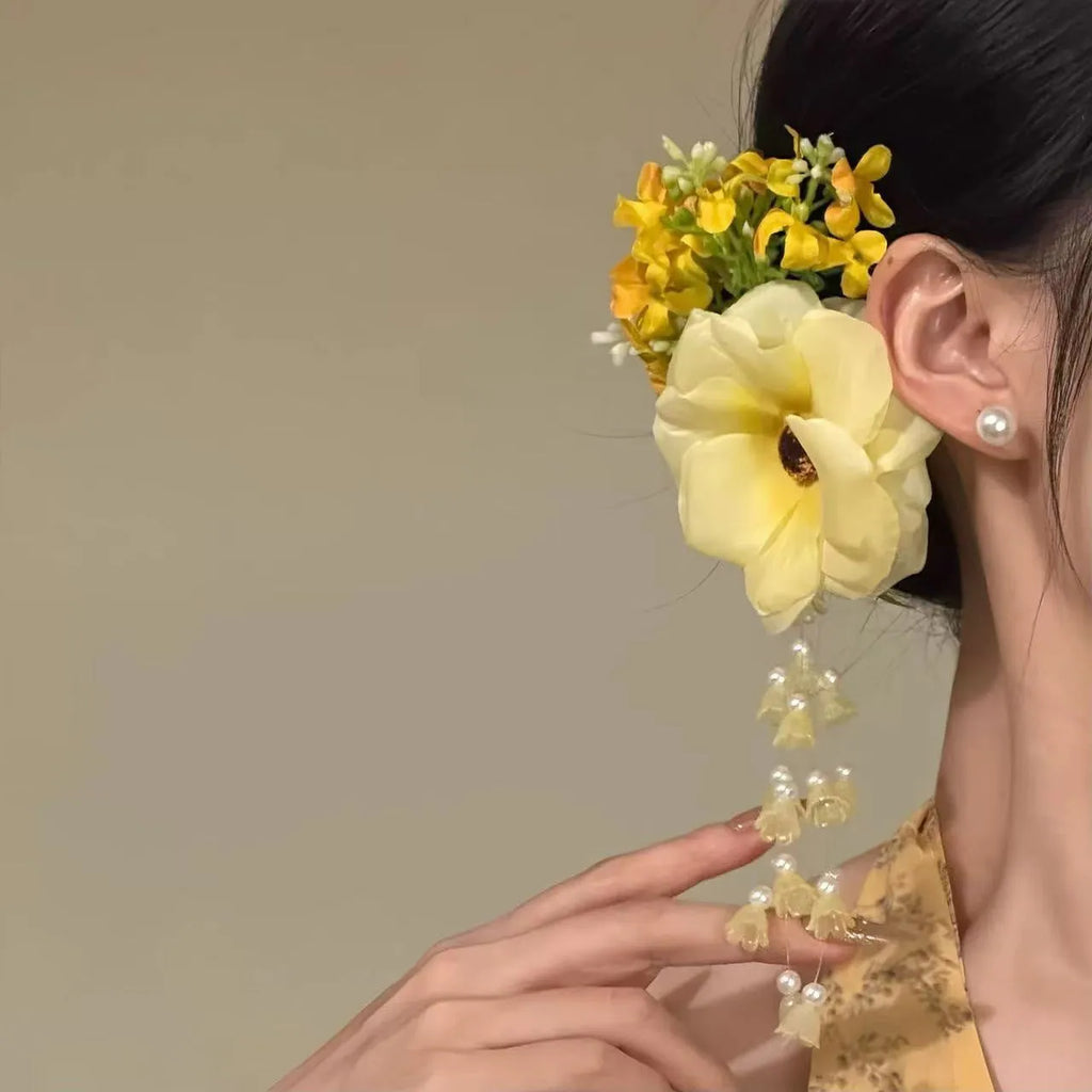 Yellow and purple flower tassel hair clip with pearl decoration on a white background.