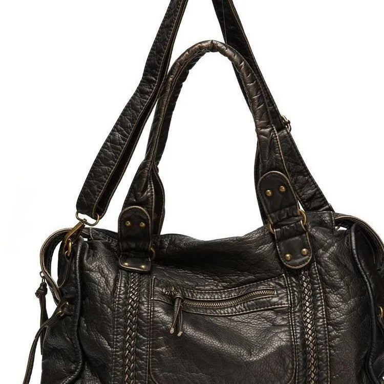 Women's European retro motorcycle messenger bag in bright black with golden edge showing weaving details and shoulder strap
