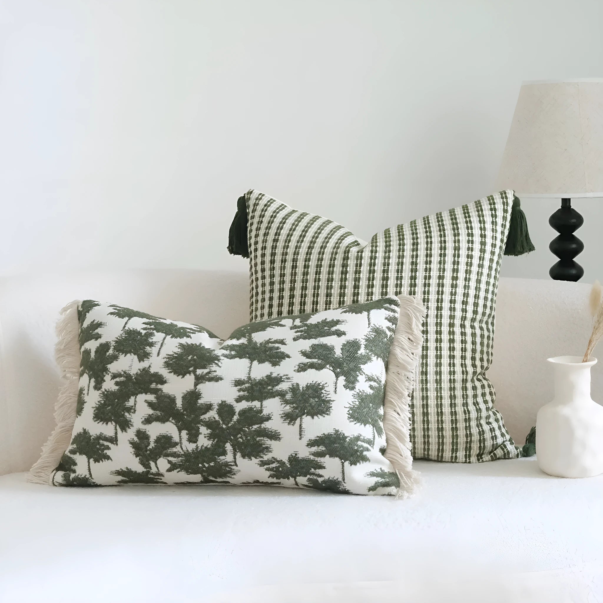 Green striped and leaf patterned hotel pillow with tassel trim on a bed.