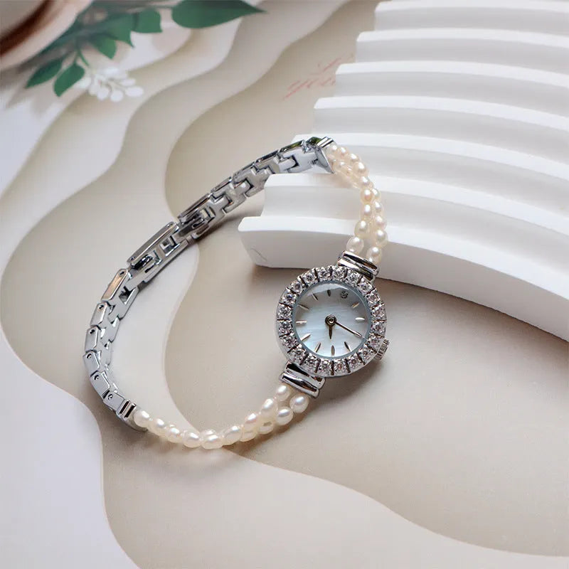 Women's light gold bracelet watch with freshwater pearls and a round 18mm dial.