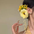 Yellow and purple flower tassel hair clip with pearl decoration on a white background.