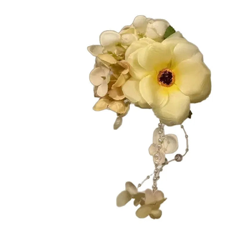 Yellow and purple flower tassel hair clip with pearl decoration on a white background.