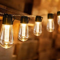 Outdoor retro string lights with glass infusion bottle bulbs hung along a black wire.