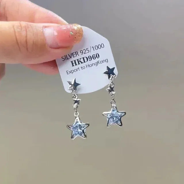Close-up of a women's geometric alloy ear clip with rhinestones, a star charm, and a tassel on a white background.