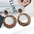 Large round cartoon-style alloy drop earrings with colourful diamond pendant on a white background.