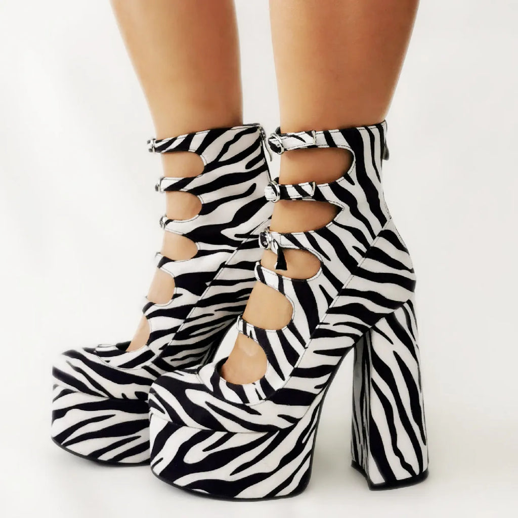 Women's black patent leather platform ankle boots with a serpentine buckle strap and thick heel.