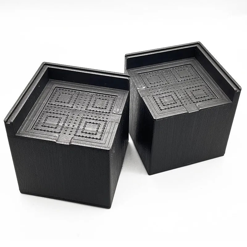 Four black plastic bed risers for increasing furniture height