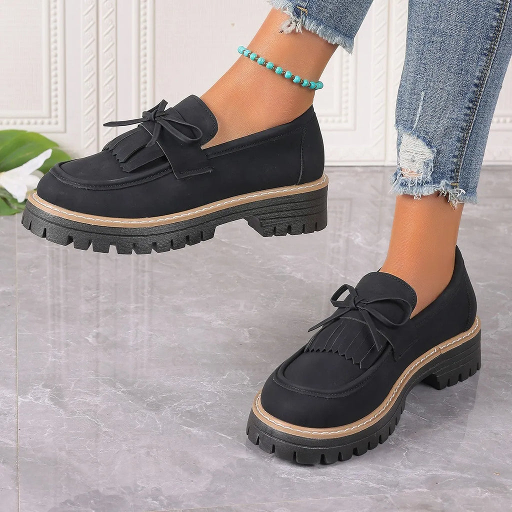 Black plus size women's loafers with a tassel and bowknot on a round toe, low top design.