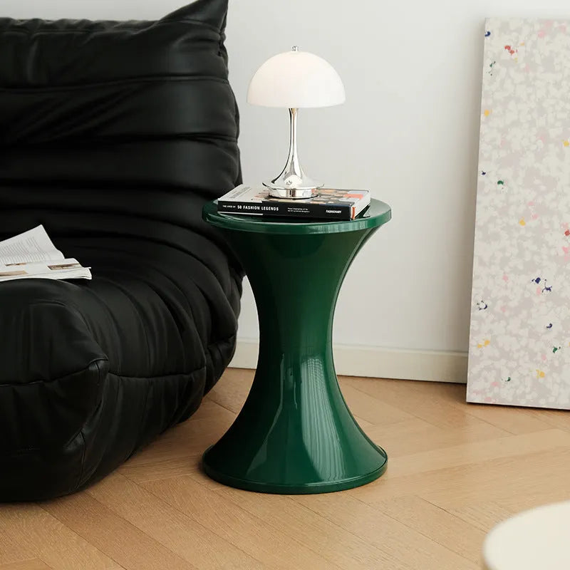 Hourglass-shaped plastic shoe changing stool with a storage seat, shown in green colour.