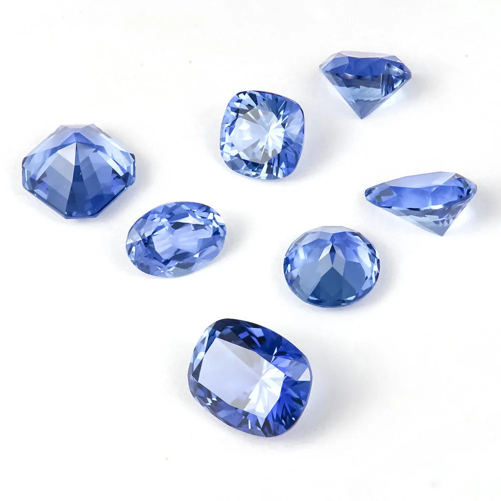 A selection of loose royal blue cultivated gemstones in heart, round, and pear shapes on a jeweller's cloth.