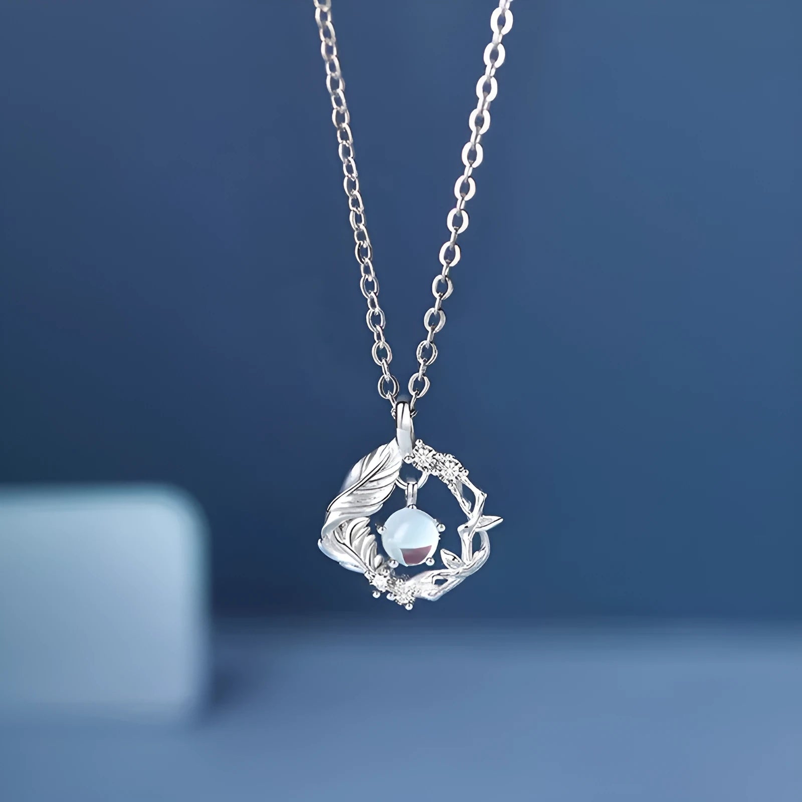 Geometric alloy pendant necklace showing a tree and bird silhouette on an adjustable chain.