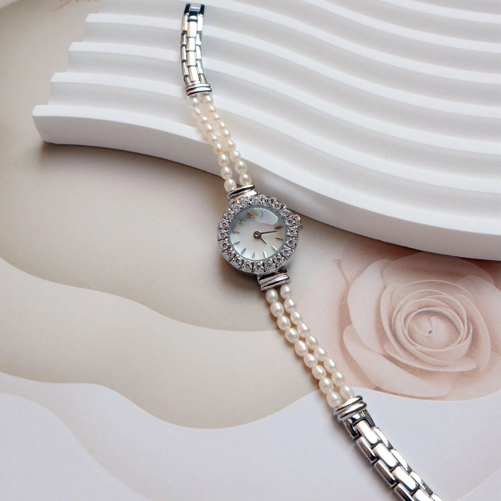 Women's light gold bracelet watch with freshwater pearls and a round 18mm dial.