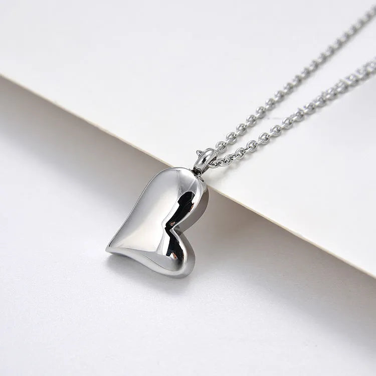 Silver curved peach heart pendant on a stainless steel necklace chain with an extension.