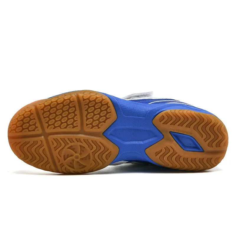 White and blue lightweight badminton shoes with a ribbed non-slip sole, shown on a court surface.