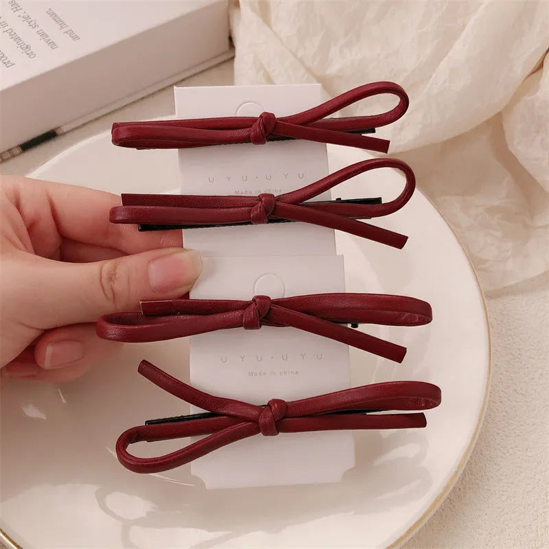 Wine red leather bow barrette hair clip shown on a model or background.