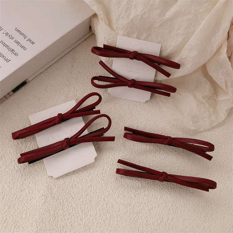 Wine red leather bow barrette hair clip shown on a model or background.
