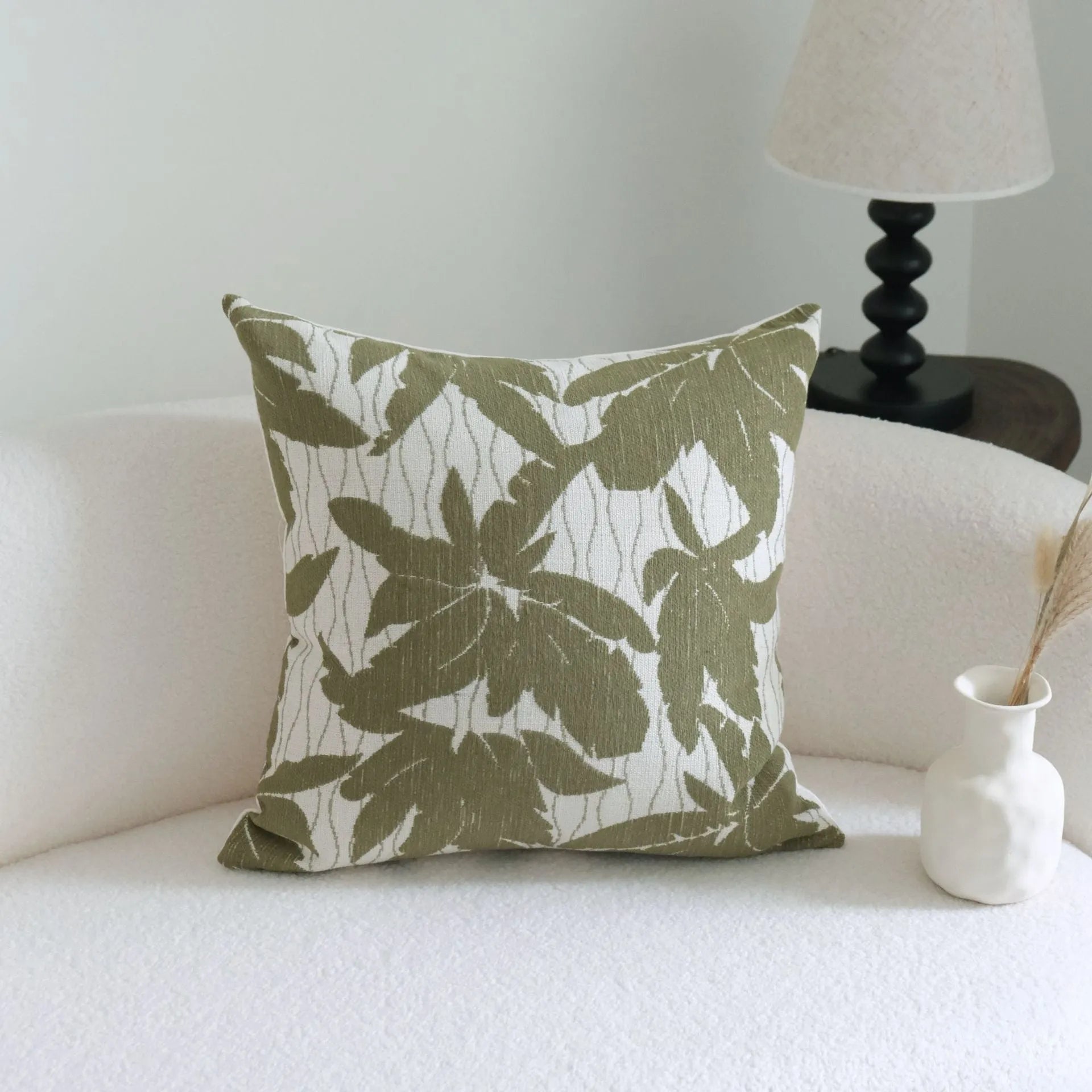 Green striped and leaf patterned hotel pillow with tassel trim on a bed.