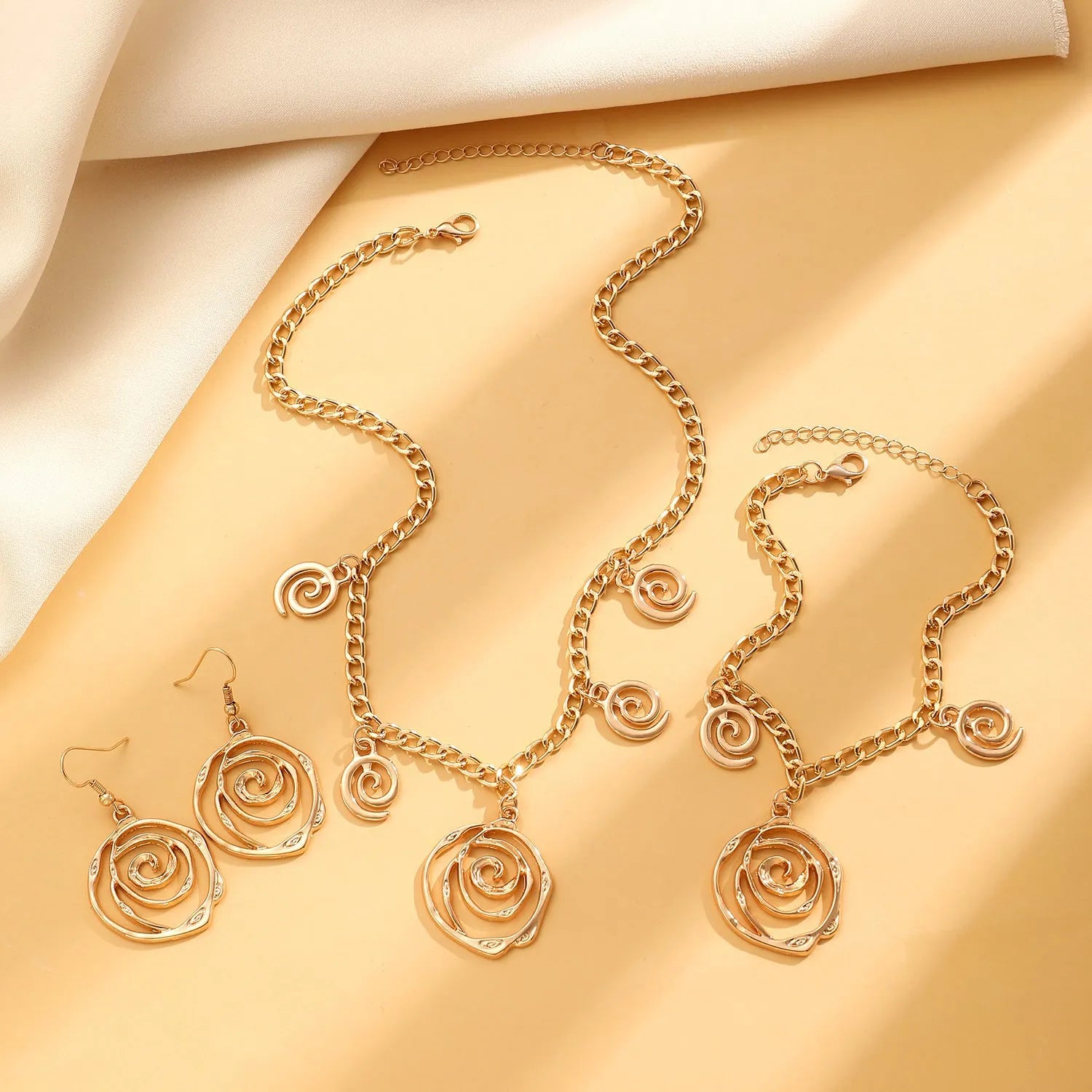 Spiral donut alloy jewellery set with necklace, bracelet, and earrings in gold or silver electroplated finish
