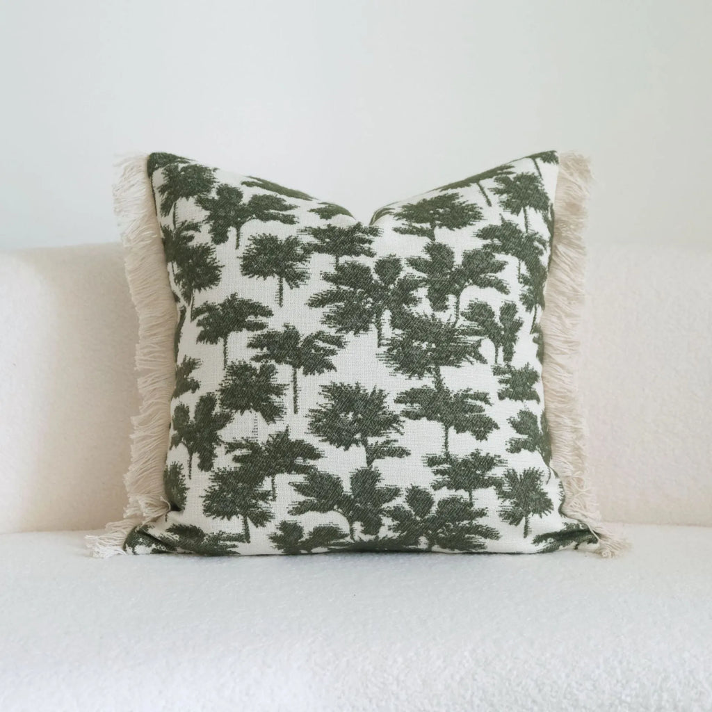 Green striped and leaf patterned hotel pillow with tassel trim on a bed.