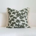 Green striped and leaf patterned hotel pillow with tassel trim on a bed.