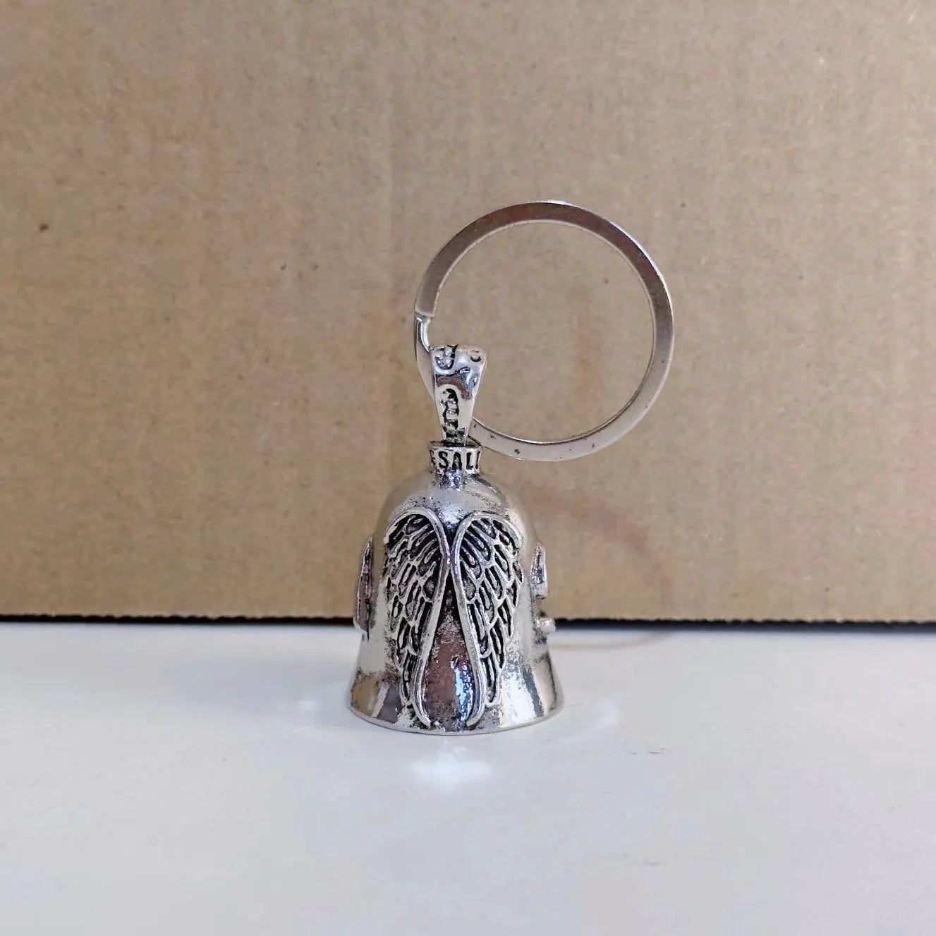 Vintage white angel feather alloy keychain and necklace on a dark background.