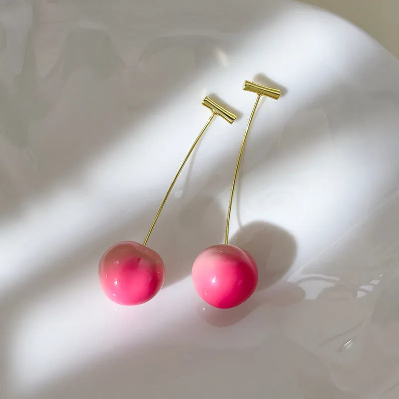 A pair of peach-shaped dangle earrings in acrylic, shown in small and large size options.