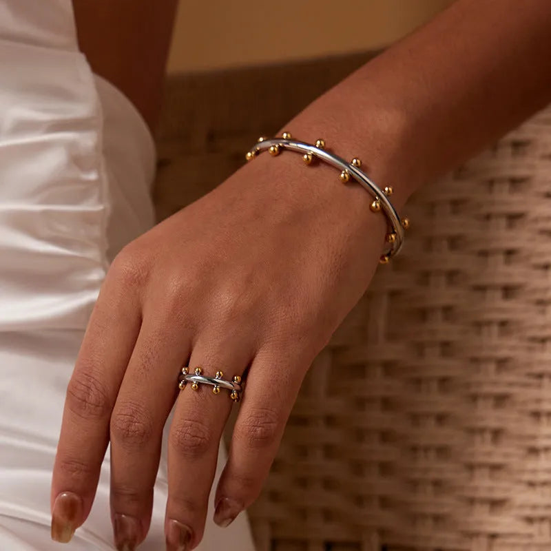 Stainless steel C-shaped bean bead bracelet with textured rivet design in gold and steel colours