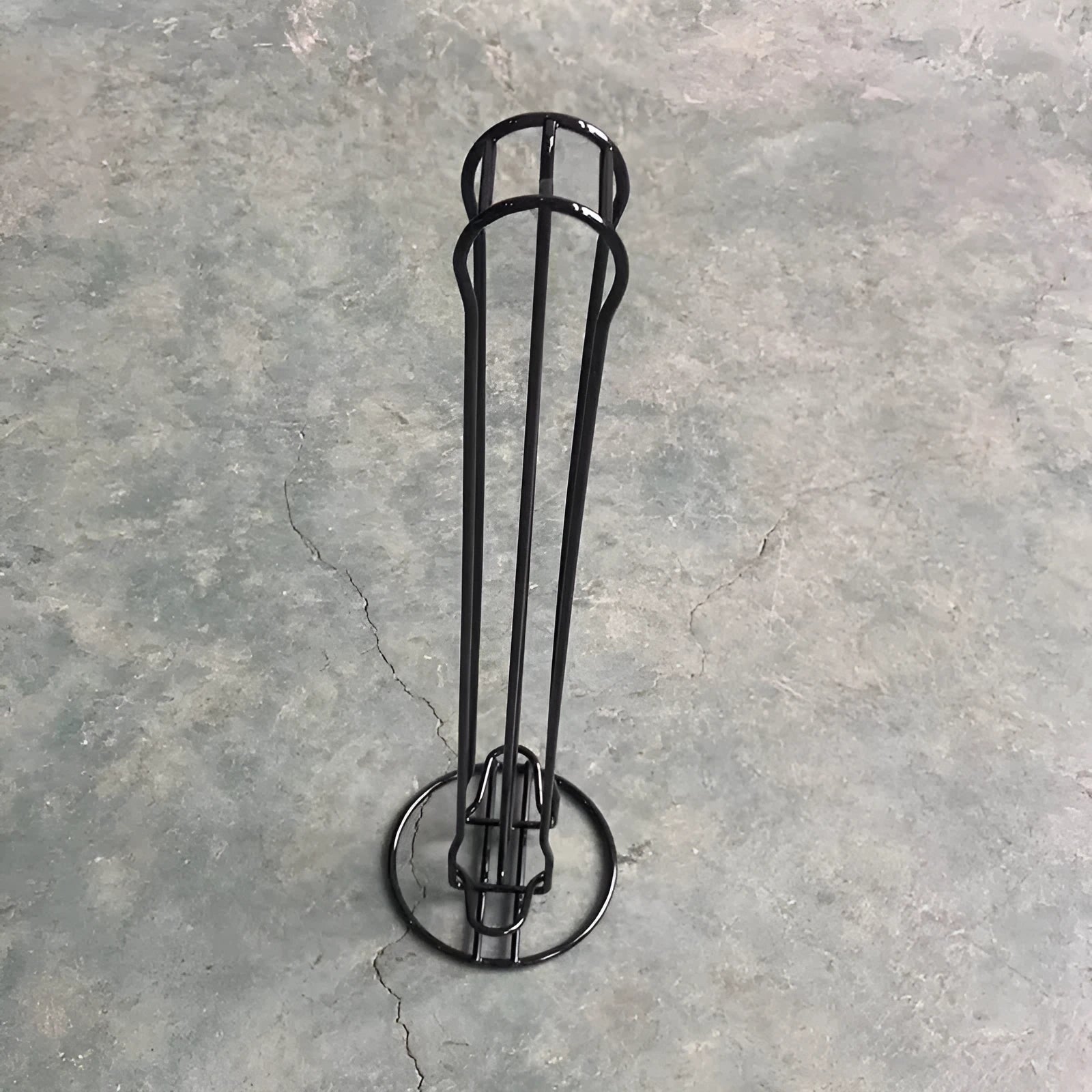 Black wrought iron coffee capsule storage rack displaying pods on a kitchen worktop.