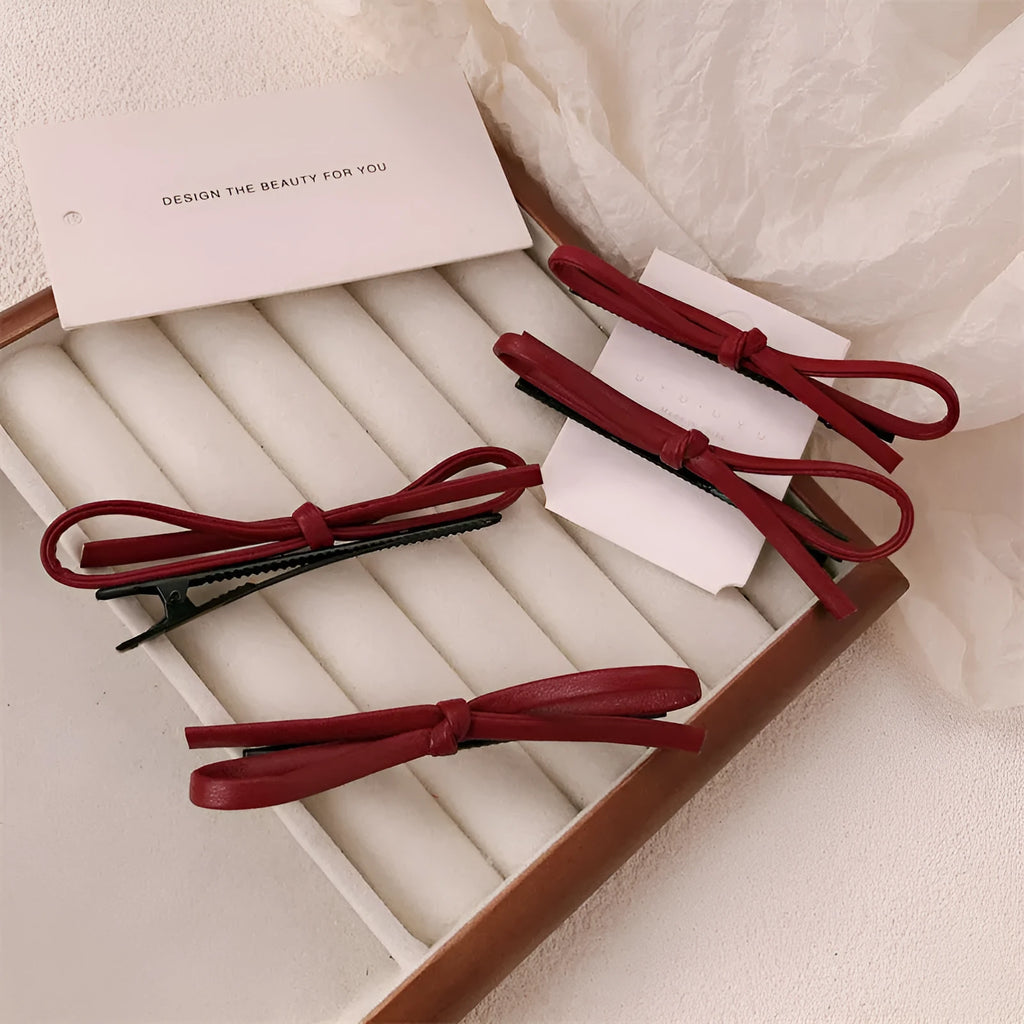 Wine red leather bow barrette hair clip shown on a model or background.