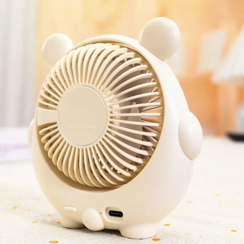 USB-powered desktop electric fan in a puppy-themed colour on a desk.