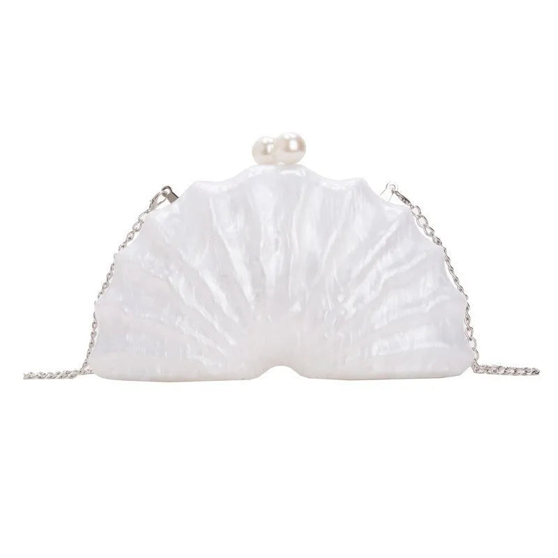 Acrylic shell-shaped clutch bag in champagne colour with chain detail on solid background