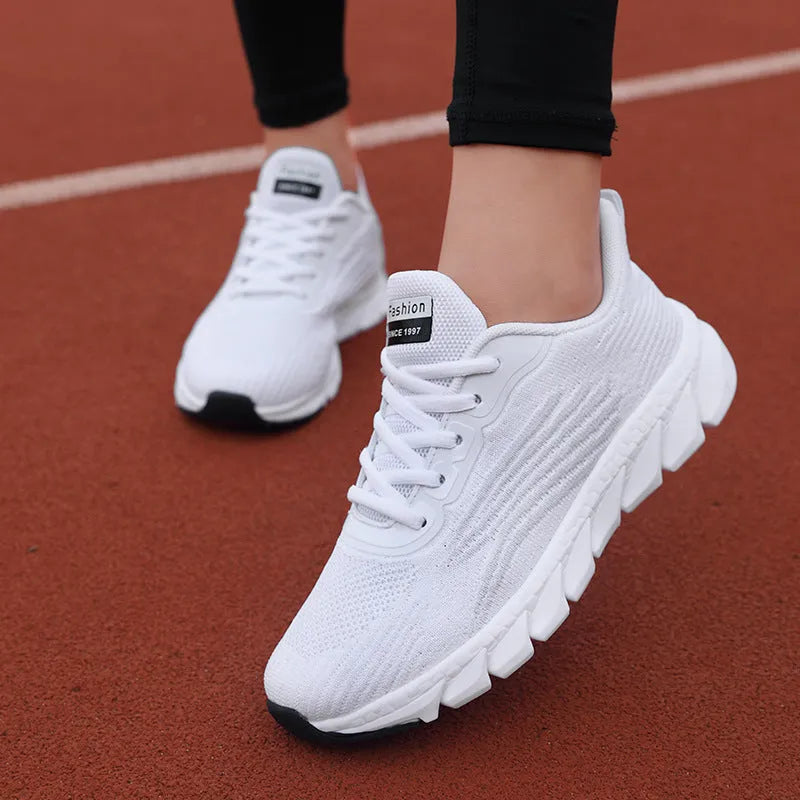 Flat running sneakers with cross-strap detail in black or white colours