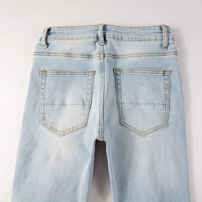 Light blue slim fit stretch men's jeans with distressed details and diamond patch pocket