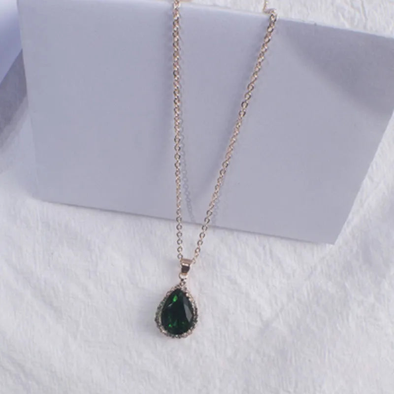 Close-up of a rose gold tone drop shape necklace with rhinestone details on a geometric pendant.
