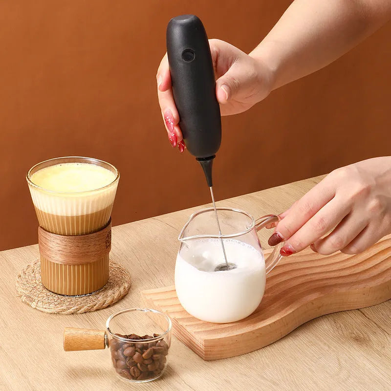 Black and white handheld electric milk frother blender for coffee preparation
