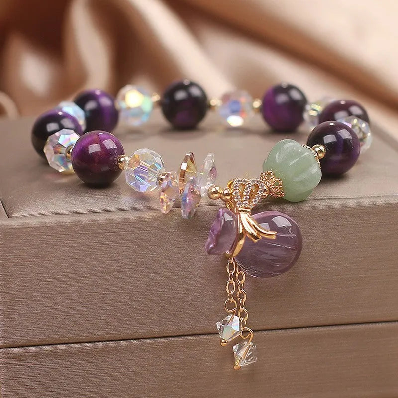 Women's purple Tigereye pendant crystal bracelet with rhinestones on a forest-style background.