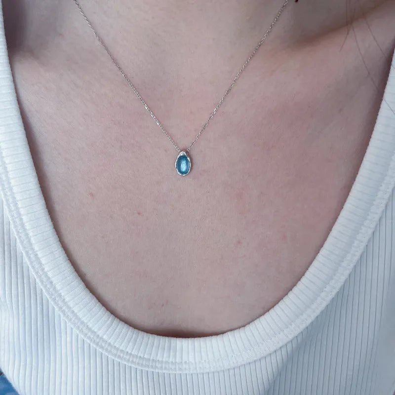 Geometric navy blue water drop pendant on an adjustable platinum-colour cross chain necklace.