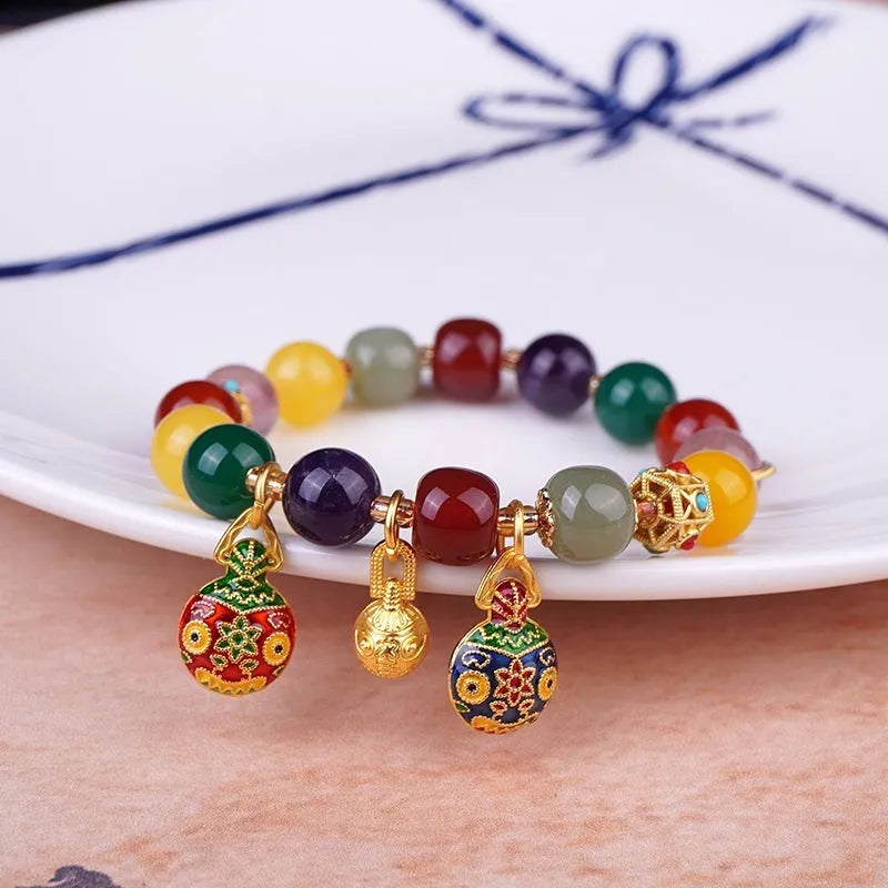 Close-up of a bracelet with a hand-woven gold beast charm and large brown agate beads.