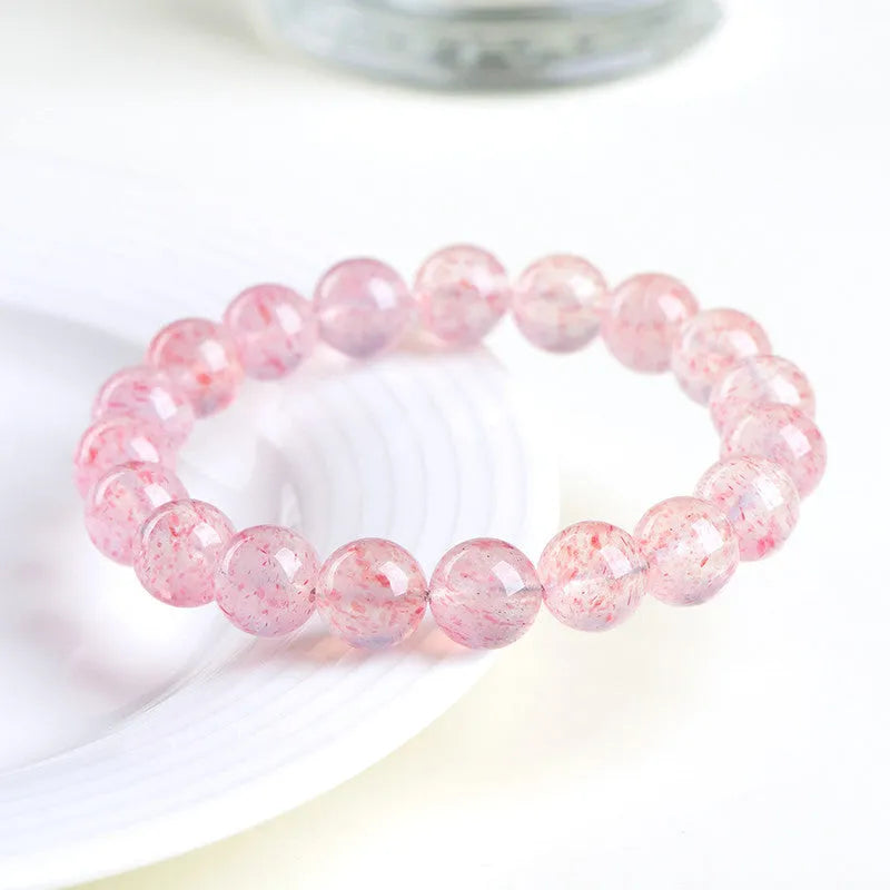 Natural white water strawberry quartz geometric ball bracelet with 10-10.8mm beads on a wrist.