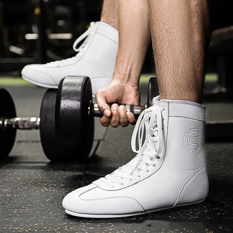 Black and gold mesh professional boxing shoes for men and women on a gym mat.