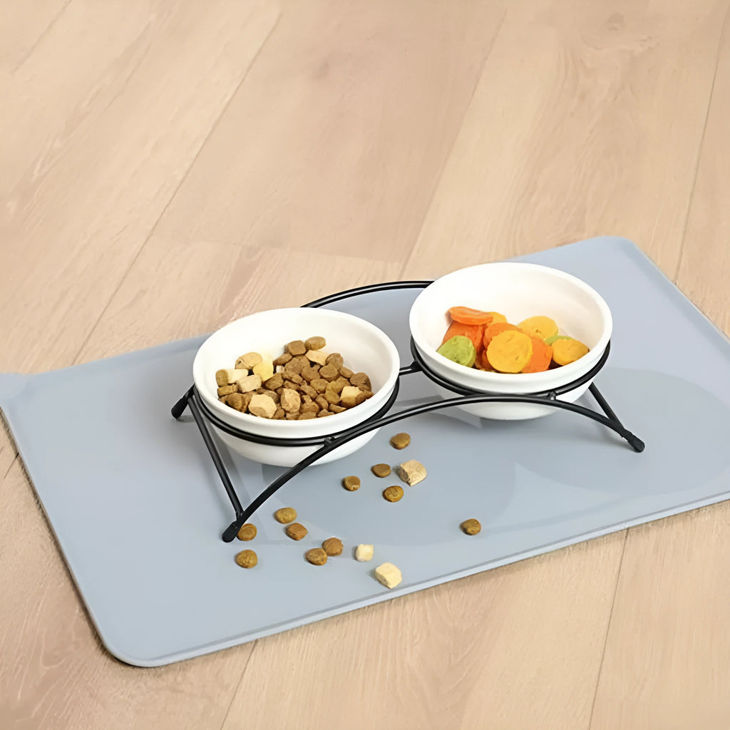 Large grey silicone pet placemat with a raised edge, holding a dog bowl on a wooden floor.