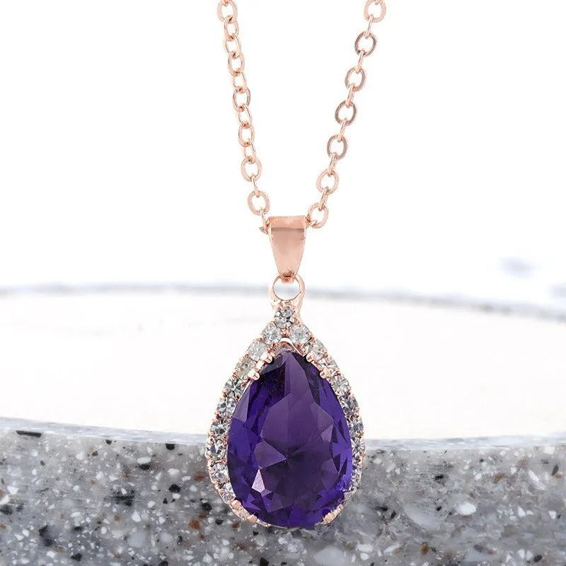 Close-up of a rose gold tone drop shape necklace with rhinestone details on a geometric pendant.