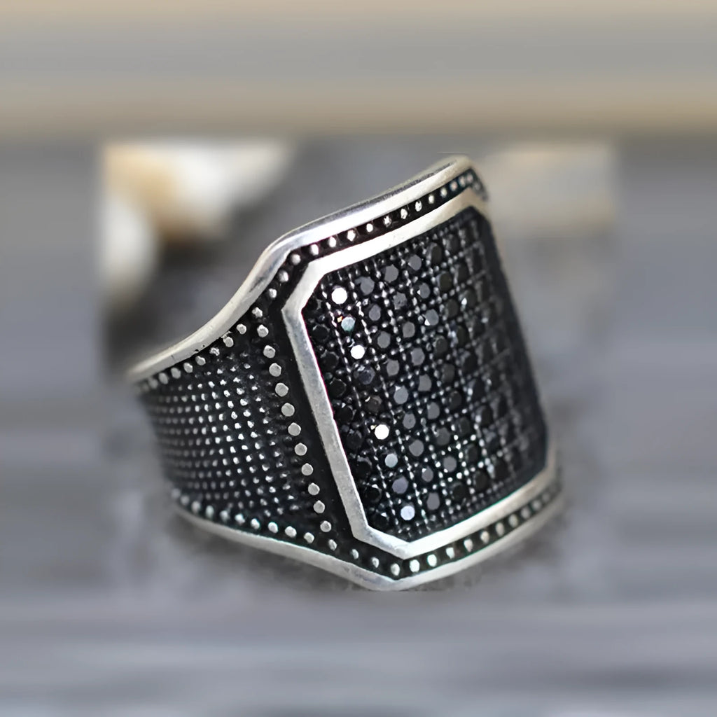 Black alloy ring with copper inlay and clear zircon stone accents on a hand.