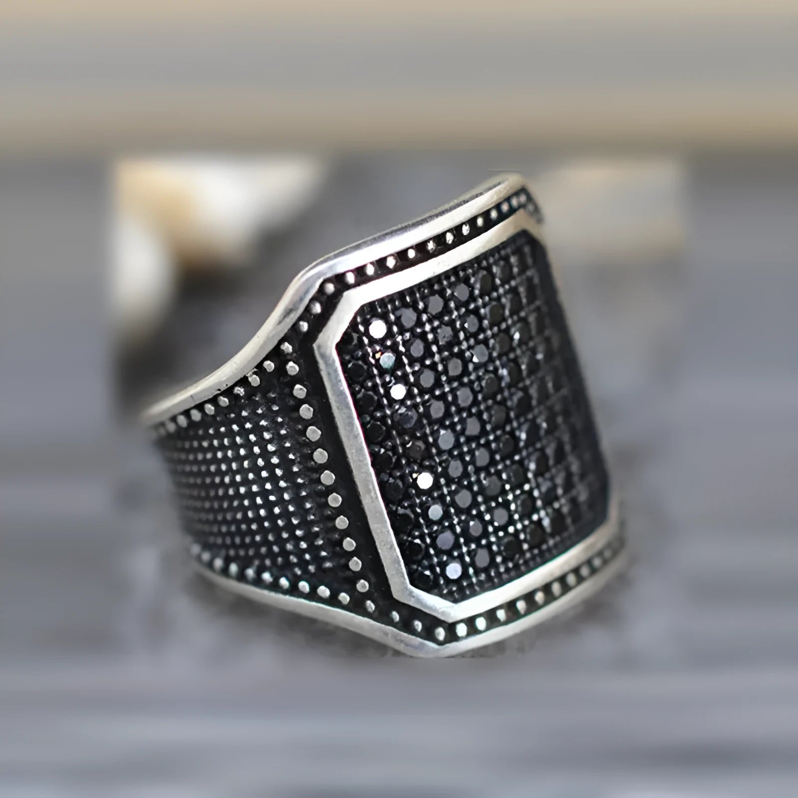 Black alloy ring with copper inlay and clear zircon stone accents on a hand.