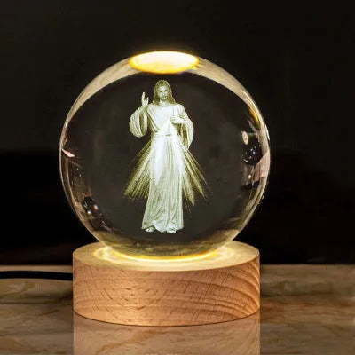 White crystal ball ornament on a wooden base with warm light, showing a detailed Cross design inside.